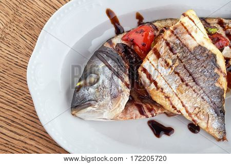 Fried Fish Dorado Garnished on Sliced Pumpkin with Basil Leaf and Sauce