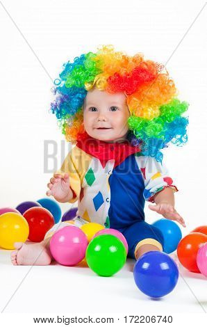 Children clown with a red nose multicolored wig in with balls. On a white background.