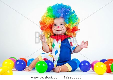 Children clown with a red nose multicolored wig in with balls. On a white background.