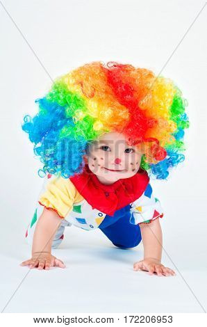 Children clown with a red nose multicolored wig in with balls. On a white background.