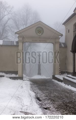 Old cross in front of the entrance to the International Shrine of St. Anna the winter fog. Mount St. Anna