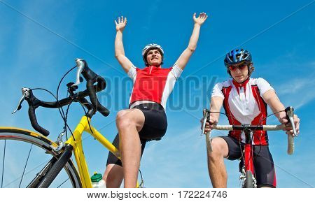 Cyclist raising his arms after crossing the finish line, inches in front of his competitor: Photo finish