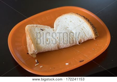 double-folded white bread sandwich with sprinkles on an orange plate