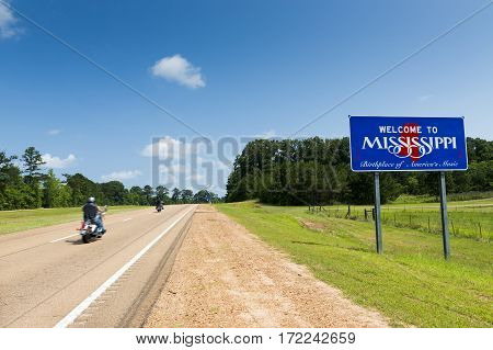 Two motorcycles passing by the Mississippi State welcome sign along the US Highway 61 in the USA; Concept for travel in America and Road Trip in America
