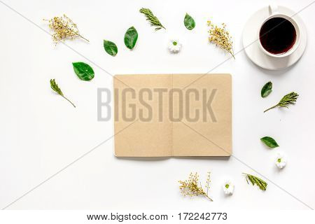 Froral flat lay with cup of coffee and craft notepaper on white background top view mockup
