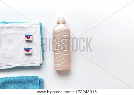 Bright clean towels pile with detergent and plastic conditioner bottles in laundry background top view mockup