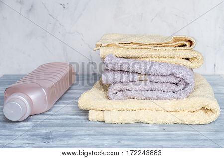 laundry set with bright towels and plastic bottels of detergent on gray table background
