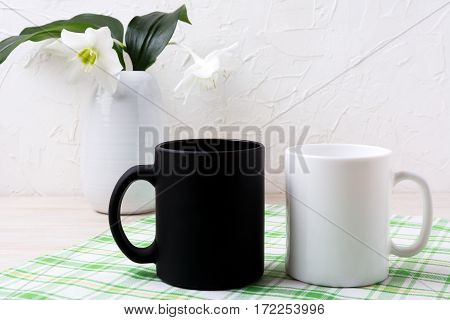 White and black mug mockup with lily in vase. Empty mug mock up for design promotion.