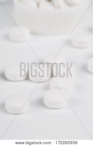 Round white pills and glass of water on a table waiting for eat