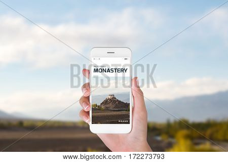woman using her smartphone for searching the travel information of beautiful Stakna monastery in the Himalayan range Leh Ladakh India. Traveling concept Beautiful Monastery blurry background.