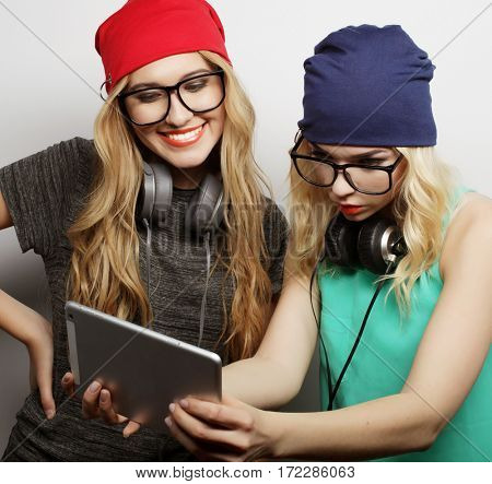 two hipster girls friends use digital tablet, studio shot over gray vackground