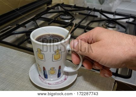 Hand with full cup of morning dose of instant coffee
