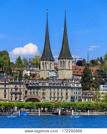 Lucerne, Switzerland - 8 May, 2016: people in boats on Lake Lucerne, towers of the Church of St. Leodegar in the background. The Church of St. Leodegar (German: St. Leodegar im Hof or Hofkirche St. Leodegar) is a landmark of the city  of Lucerne.