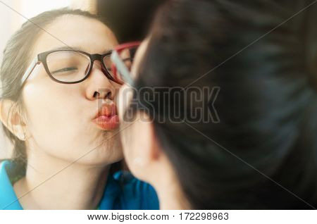 Asian woman kissing on the mirror. Eyeglasses girl kissing on the mirror.
