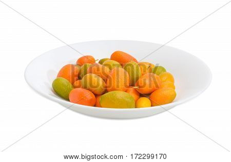 Fresh oval kumquats on a white dish on a light background