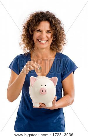 Portrait of a happy middle aged woman puting some money on a Piggybank
