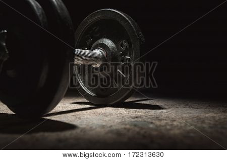 In the dark mood, Close up of dumbbell with lighting and shadow on black background. Copy space.
