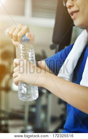 Asian woman holding bottle of water for drink after workout in the gym.