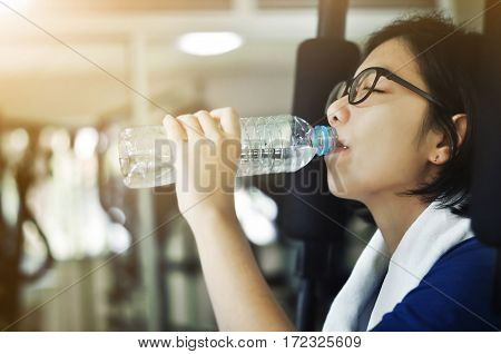Asian woman drinking water after her workout in the gym.