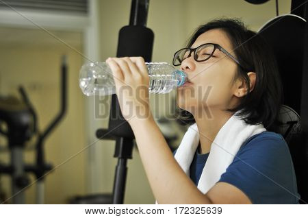Asian woman drinking water after her workout in the gym.