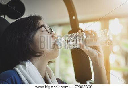 Asian woman drinking water after her workout in the gym.