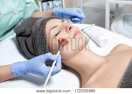 beautician applies face mask with a brush to the beautiful young woman in Spa salon. cosmetic procedure skin care. Microdermabrasion