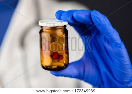 Female doctor holding unlabeled bottle of various pills and medication prescription medicine and healthcare selective focus