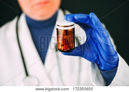 Female doctor holding unlabeled bottle of various pills and medication prescription medicine and healthcare selective focus