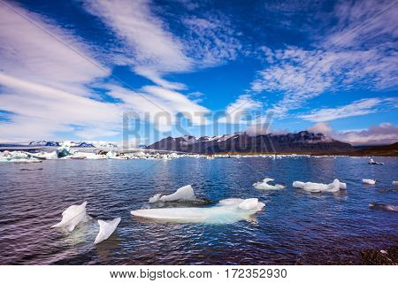 The ice floes and clouds of lagoon Jokulsarlon, Iceland. Clouds cirrocumulus reflected in the water of lagoon. The concept of northern extreme tourism