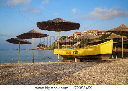 Nesebar Bulgaria - September 05 2014: Straw beach umbrellas and rescue boat on a pebble beach. Seaside resort and ancient old town Nesebar in Bulgaria. Bulgarian Black Sea Coast.