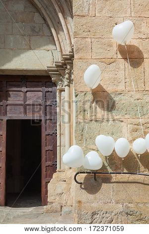 For a wedding is the entrance of a church in Largentiere in the Ardeche region of France decorated with white heart-shaped balloons