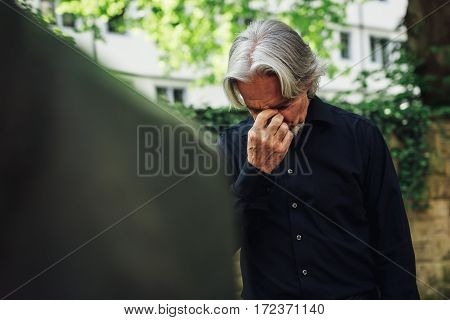 Senior man mourning by a beloved's grave