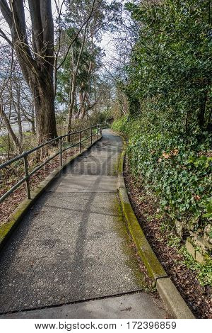 A view of a sidewalk leading the water at Lincon Park in West Seattle Washington.