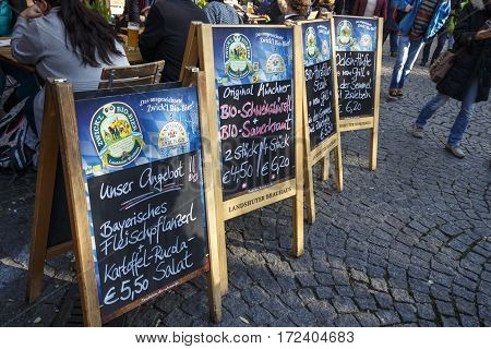MUNICH, GERMANY - OCTOBER 31, 2015: Outdoor seating area of a restaurant at the Viktualienmarkt with tablets of food offers in front