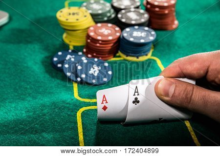 casino gambling poker people and entertainment concept - close up of poker player with playing cards and chips at green casino table