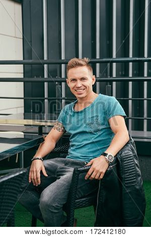 portrait of handsome man in a blue T-shirt outside building in summer