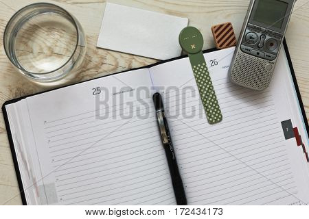 Typical journalist's accessories - lined scetchbook with colored bookmarks dictaphone glass of water and so on