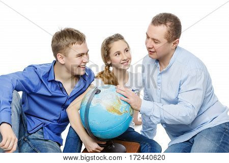 Beautiful teen boy and girl in casual clothes sitting on floor with father looking for something on the Earth globe. Isolated on white background. Copy space.