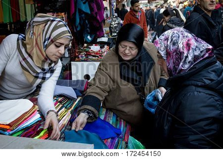 ISTANBUL TURKEY - DECEMBER 28 2015: Group of women wearing islamic headscarf negotiating clothe at a fabric merchant on a bazaar on the European side of the city