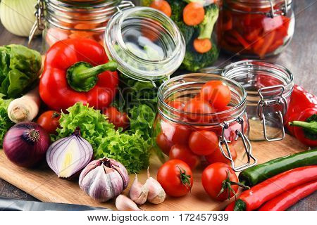 Jars With Marinated Food And Raw Vegetables On Cutting Board