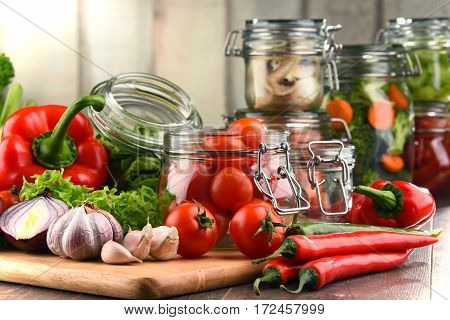 Jars With Marinated Food And Raw Vegetables On Cutting Board