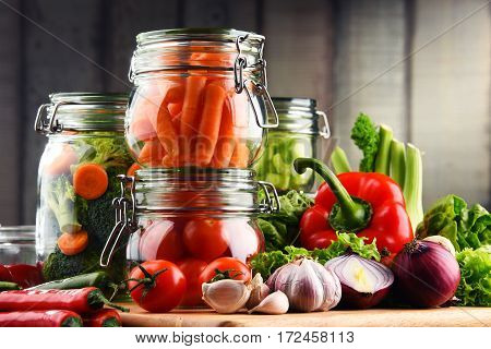 Jars With Marinated Food And Raw Vegetables On Cutting Board