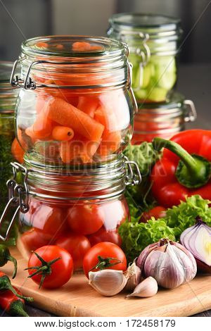 Jars With Marinated Food And Raw Vegetables On Cutting Board