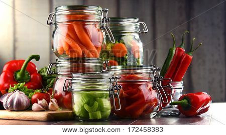 Jars With Marinated Food And Raw Vegetables On Cutting Board