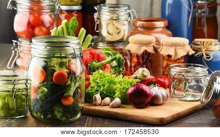 Jars With Marinated Food And Raw Vegetables On Cutting Board