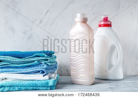 laundry set with bright towels and plastic bottels of detergent on gray table background mock up