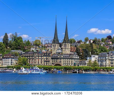 Lucerne, Switzerland - 8 May, 2016: people in boats on Lake Lucerne, towers of the Church of St. Leodegar and buildings of the city in the background. Lucerne is a city in central Switzerland, it is the capital of the Swiss canton of Lucerne.
