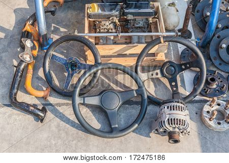 Old automobile machine parts steering wheels and used machine parts place on street walk in second hand market for selling.