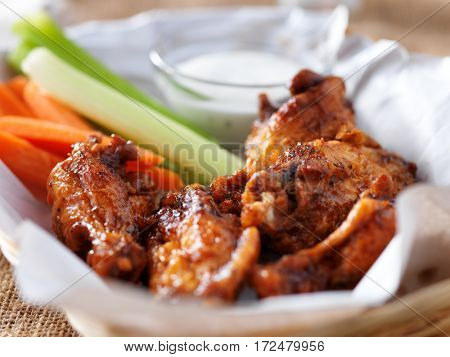 bbq buffalo chicken wings in basket, with ranch dip, carrot and celery sticks