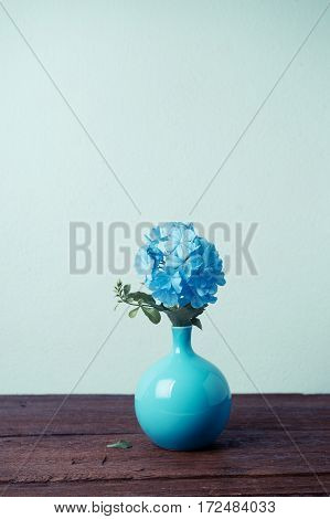 Blue plumbago flowers in vase (Cape Leadwort or Plumbago auriculata) on wooden table. vintage tone.